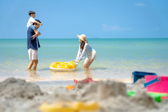 Multigenerational Asian family enjoying summer beach vacation, playing and relaxing together.