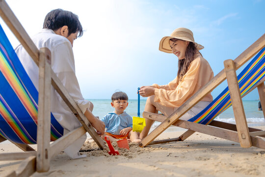 Multigenerational Asian family enjoying summer beach vacation, playing and relaxing together.