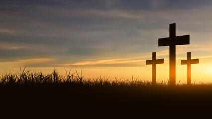 A silhouette of a Christian cross stands on a grassy hill under a dramatic sky with glowing sunset light breaking through the clouds. A symbol of faith, hope, and spirituality © Leo Lintang