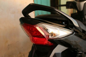 Fototapeta premium Rear close-up of a Honda motorcycle highlighting the red tail light, sleek body design, and rear handle. Captured with soft natural lighting and shallow depth of field in a garage environment