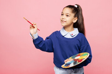 Little kid girl 8-9 years old wear blue shirt have fun hold in hand palette paint look aside...