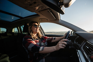 Woman driving car enjoying sunny road trip