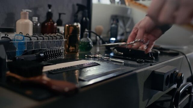 Close up of anonymous barber taking professional scissors and comb during workday
