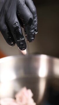 Cocinero profesional con guantes de l&aacute;tex negro fr&iacute;e peque&ntilde;os trozos de grasa de jam&oacute;n ib&eacute;rico en una sart&eacute;n de acero inoxidable, generando un chisporroteo intenso y aromas ricos durante la cocci&oacute;n.