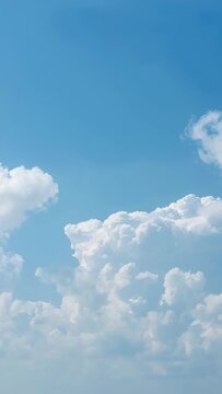 Vertical video: Drifting cumulus bank shifting in blue sky, light wind moving small puff at right