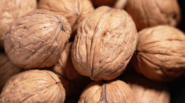Pile of walnuts close up. Whole nuts in natural shell. Healthy food ingredient and nutrition concept. Rotation