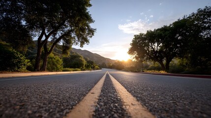 A paved road winds through a scenic landscape at golden hour bathed in warm sunlight