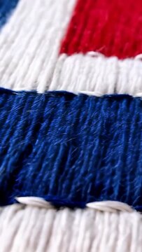 Vertical video: Sweeping macro lens revealing fabric patch on desk showing red white blue stitches