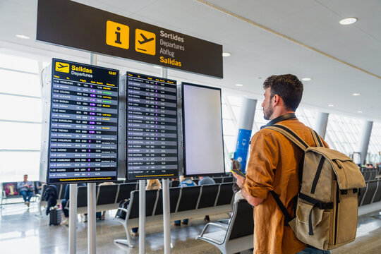 Male traveler checking flight departures board in airport