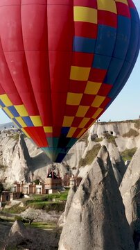 Colourful Red Blue Yellow Colours Hot Air Baloons Aerial Drone Flight. The great tourist attraction of Cappadocia. Cappadocia landscape with rocks and houses. Goreme, Cappadocia, Turkey.