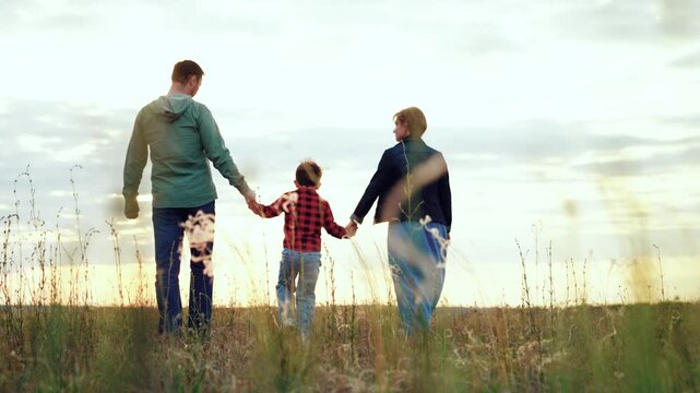 Family cherishes relaxed walk in field. Family holds hands strolling across grassy valley embodying unity family of bond. Family vacation filled with active and enjoyable pastimes strengthen ties