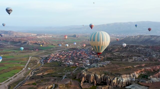 Colourful Red Blue Yellow Colours Hot Air Baloons Aerial Drone Flight. The great tourist attraction of Cappadocia. Cappadocia landscape with rocks and houses. Goreme, Cappadocia, Turkey.