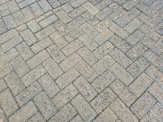 Pattern of gray interlocking concrete paving stones forming textured outdoor walkway or driveway surface background