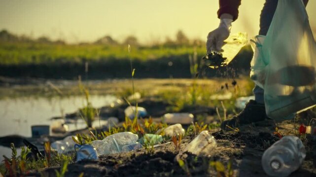 A devoted male volunteer, an environmental activist, diligently sorts refuse, including plastic bags and bottles, after a garbage cleanup activity on a serene pond shore at dusk