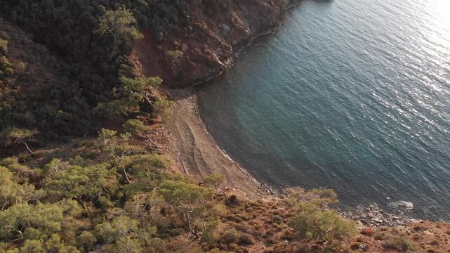 Scenic aerial shot descending over a lush forest towards the turquoise mediterranean sea coast, ab01