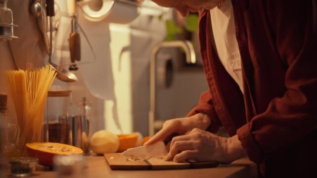 In a bustling kitchen, a skilled young chef expertly minces fresh garlic cloves with a ceramic knife, releasing the spice's potent aroma and unleashing its antiseptic benefits