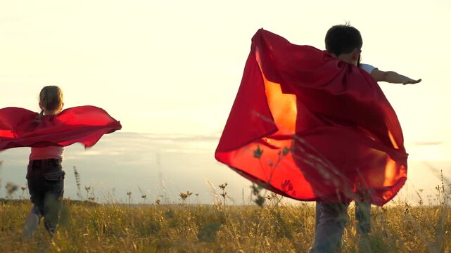 happy family superhero costumes run into sunset park. childhood dream defeat evil. play good guy. childish fantasy. mother girl boy son daughter run. teamwork. family superheroes run help happy family