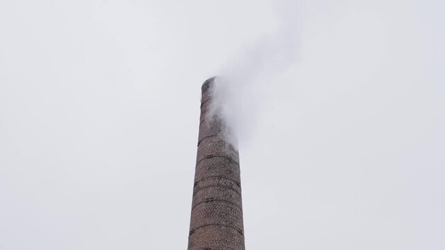 smoke streams from brick chimney on cloudy day, slow motion
