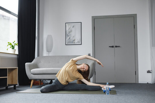 Portrait of young woman doing yoga at home on a mat