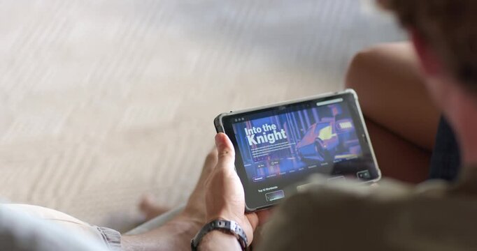 As title screen is appearing, hands are holding tablet on couch, adjusting to select game menu