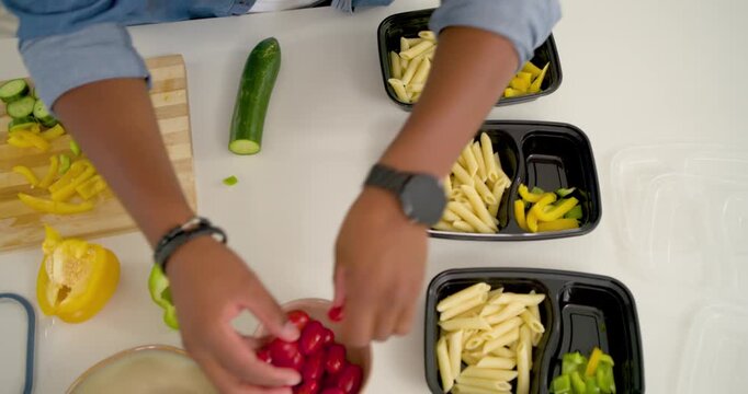 Vertical video: Reaching tomatoes, African American man prepping three prep boxes on counter