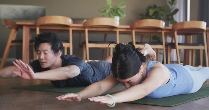 Vertical video: Couple starting reaching arms forward, holding prone hold on green mats for health