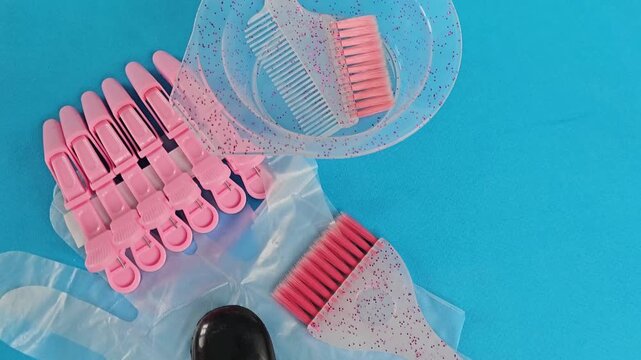Tools for hair dyeing and styling preparation on a blue surface with pink items and accessories