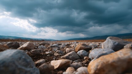 Obraz premium Close up of a rocky terrain stretching towards the horizon under a dramatic overcast sky filled with dark moody clouds emphasizing texture and