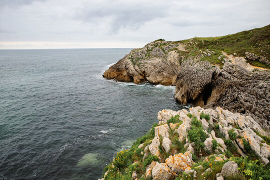 Rocky cliff overlooking the ocean with a coastal path and calm sea