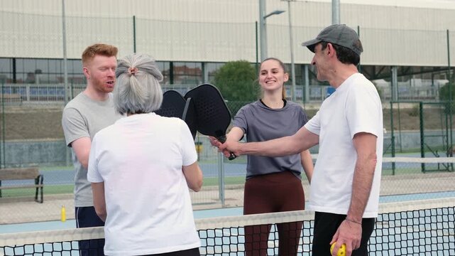 Four friends greeting each other with a handshake before playing a game of pickleball