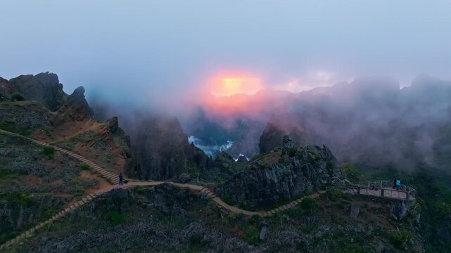 Mountains on sunset covered in fog and clouds with blooming Cytisus shrubs. Near Pico de Arieiro , Madeira island, Portugal. Push in approach dolly move