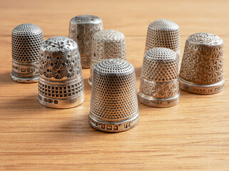 Collection of antique sterling silver hallmarked English sewing thinmbles on a desk top backkground