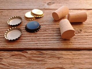 Close up of some wine bottle corks and crown caps on a wooden table.