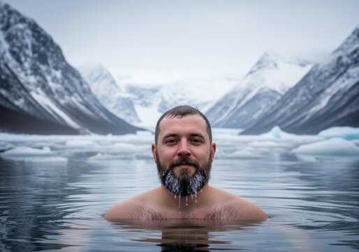 Man with beard in icy cold water with snowy mountains