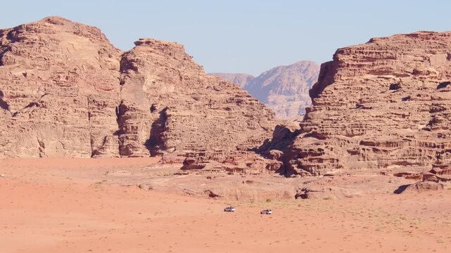 Wadi rum desert landscape with line of 4wd vehicles drive from sunset viewpoint on organized sunset tour in Jordan