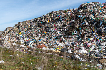 Large Pile of Mixed Waste and Trash in Open Area Under Clear Blue Sky During Daytime