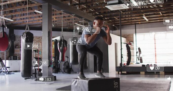 Vertical video: Bending knees, man blue shirt doing plyo jumps in boxing gym for power with metrics