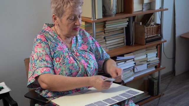 Elderly senior woman plays a card game of solitaire.