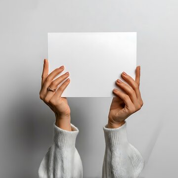 Person holding a blank white card in front of their face with both hands
