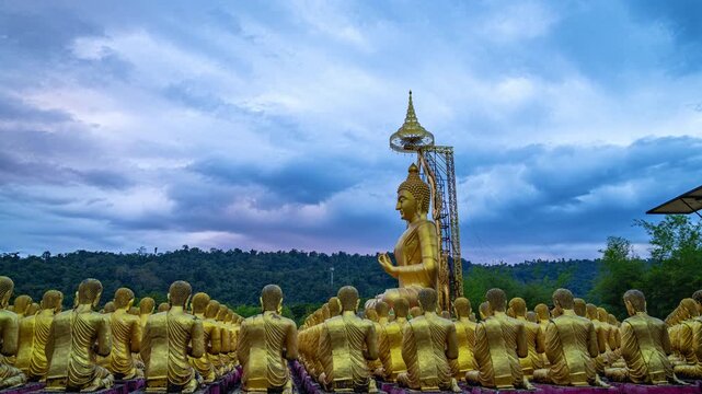 The grand Ovāda Pātimokkha Buddha image dominates the grounds, with rows of small statues creating a powerful visual of unity and faith Serene Golden Buddha Statue Against Dramatic Cloudy Sky