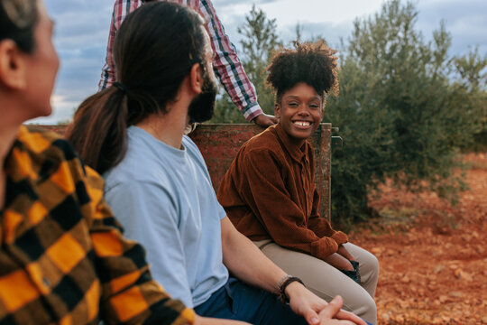 Smiling young woman and friends harvesting olives together in an autumn olive grove