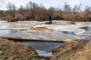 Melting river ice and drifting ice floes during early spring thaw in natural rural landscape © Edijs