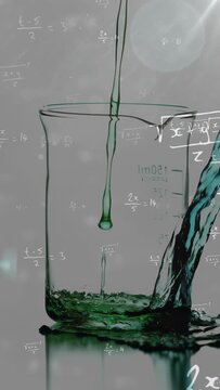 Vertical video: Glass beaker filling as stream above forming droplets and side pour raising level