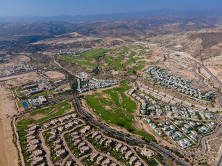Obraz premium Aerial drone view of the beautiful Taghazout Bay coastline featuring luxury resorts, sandy beaches, lush green golf courses, and the Atlantic Ocean in Agadir, Morocco.