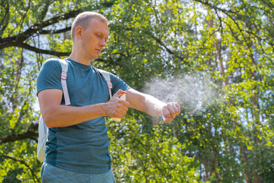 Man applying insect repellent spray in forest setting