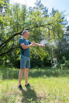 Man applying insect spray in a forest clearing