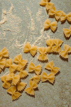 Italian farfalle pasta scattered on a rustic surface