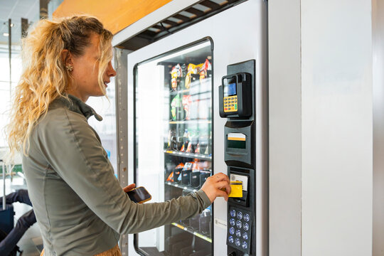 Woman at airport vending machine using payment card