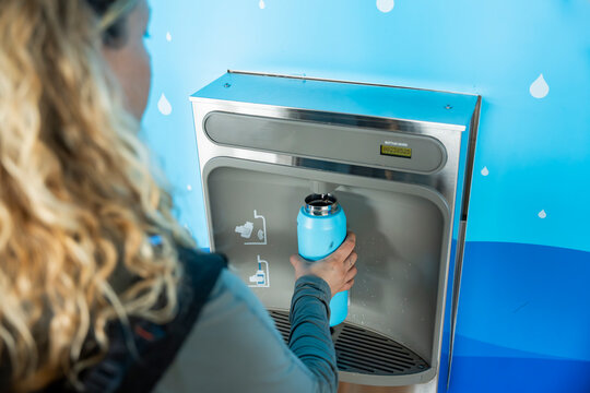 Woman refilling water bottle at airport hydration station