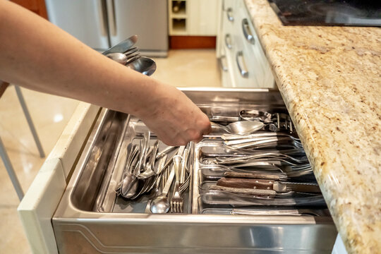 Hand organizing cutlery in a kitchen drawer
